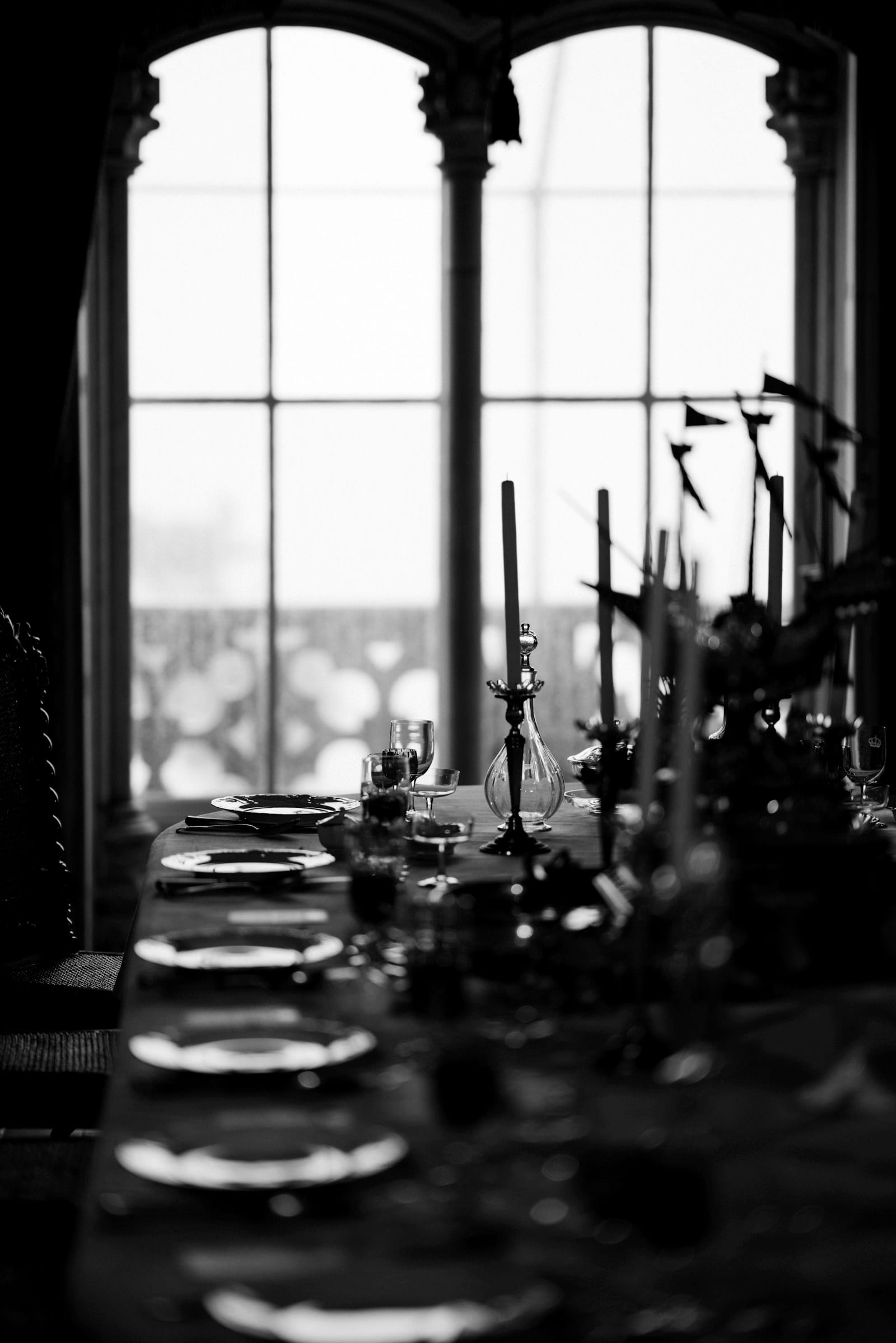 Taper candles glowing on a styled table by a window